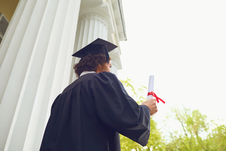 Happy graduate with diploma in hand smiling at university background. Graduation.University gesture and people concept.の写真素材