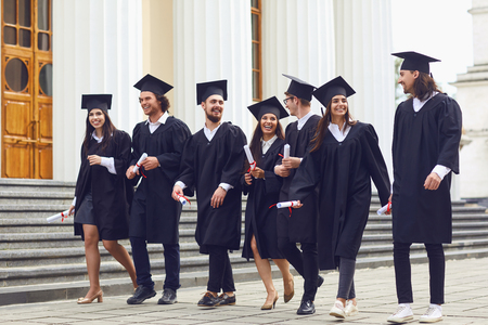 Group of students graduates go smiling against the background of university college. Graduation.University gesture and people concept.の写真素材