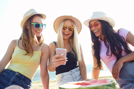 Friends at a party do selfie on the phone on the beach in the park in the summer.の写真素材