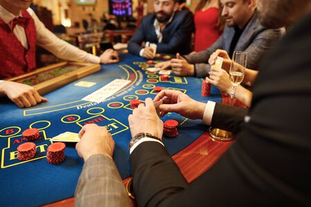 People play poker at the table in the casino. Hands with cards in the hands of a game in a casino.の写真素材