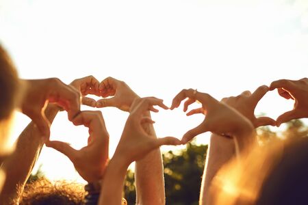 Hands of group people in the shape of a heart against the sunset. Love and relationship friendship...