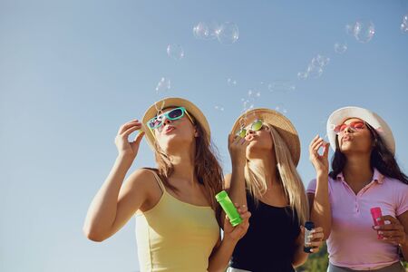 Girlfriends cheerful blowing soap bubbles on the beach in summer park.の写真素材