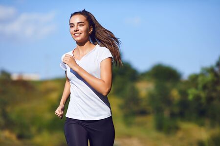 Girl runner runs along in nature in summer. Jogging in the morning. Active lifestyle.
