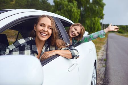 A group of happy friends travelers are driving in a car on road.の写真素材