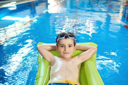The boy smiles in the swimming pool indoors.の写真素材