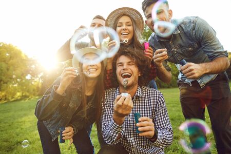 Funny friends with soap bubbles in the park in summer spring in the autumn.