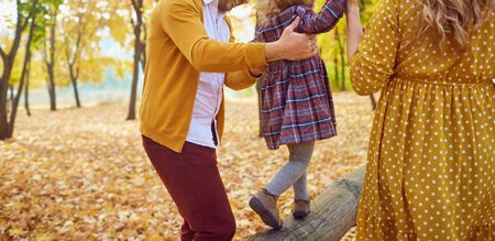 Family playing with their daughter on nature in the fall.の写真素材