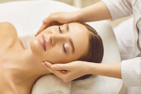 Face woman massage relax close up. Beautiful woman has a facial massage in a beauty clinic. Cosmetology skin care.の写真素材