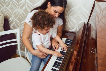 Mother teacher teaches the child to play the piano. Piano lesson.の写真素材