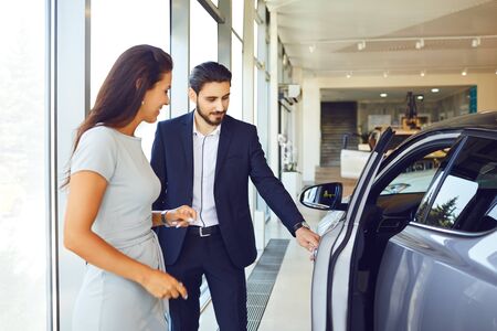A young woman buys a new car in an auto salon.の写真素材