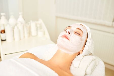 Facial skin treatment with a cosmetic mask in a beauty salon. A woman is relaxing in the spa salon.