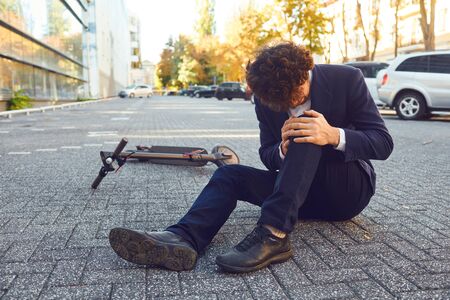 Accident with an electric scooter. A man fell from a scooter on a city street. Trauma in incident.の写真素材