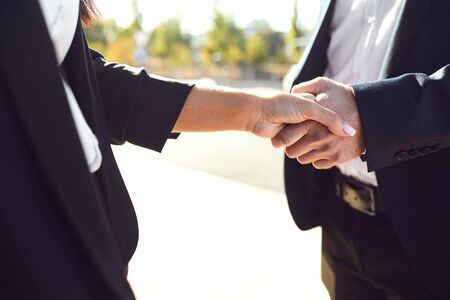 Handshake business. Businessman and business woman make handshakes while standing outdoors at a...