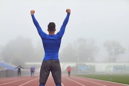 The guy the athlete raised his hands up at the stadium in the fog. The concept of victory of success motivation good luck in sports.の写真素材