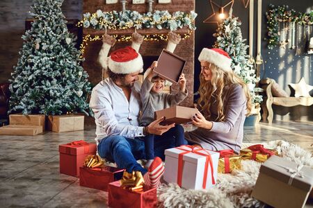 Parents gives a child a gift box in the house at Christmasの写真素材