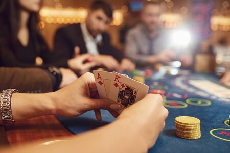 Close-up hands of a poker player checking cards on a table in a casino.の写真素材