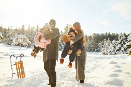 Woman and man with children having fun in winter forest playing with snow in sunlightの写真素材