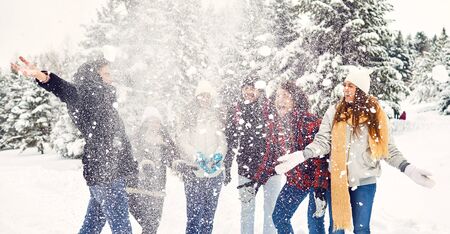 Happy friends throw fun snow in the park in winterの写真素材