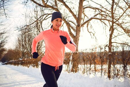 Girl runs on nature in winter. Woman in sportswear jogging in winter
