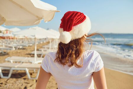 Girl in santa hat on the sea beach. Christmas concept on vacation.. The concept of Christmas by the sea.の写真素材