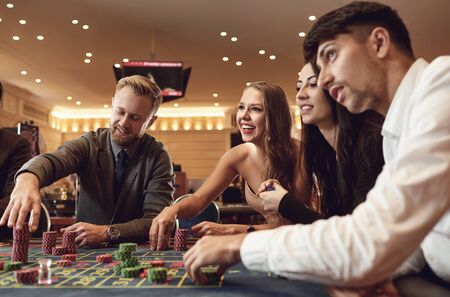 Happy people are betting in gambling at roulette poker in a casino. Gambling betting in casino...