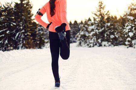 Happy young woman stretching before running in the winter parkの写真素材