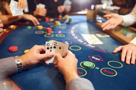 Close-up hands of a poker player checking cards on a table in a casino. Roulette game betting...