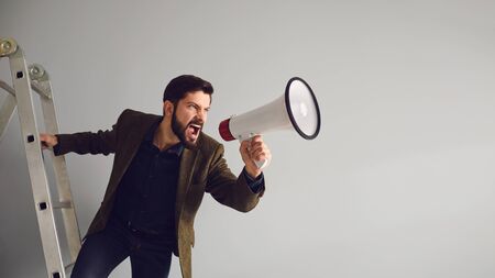 Businessman on the stairs with a megaphone in hand shoutsの写真素材