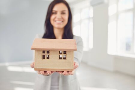 Woman seller broker realtor agent is a realtor with keys in hand against the background of a white real estate room apartment home. Sale purchase rent real estate mortgage.の写真素材