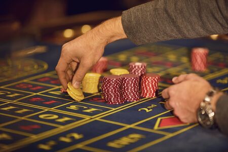 A player plays roulette in a casino. Close-up hand with chips on a roulette table. Gambling.Casino...