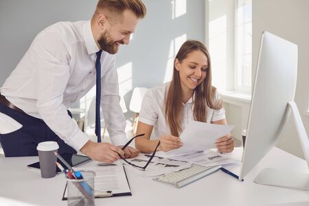 Positive businessman and businesswoman smiling working in a white office. Businesspeople work...