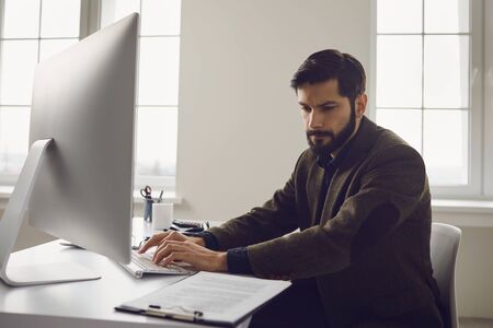 Businessman works at the computer at the table in the workplace in the office.