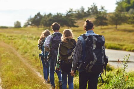 A group of tourists with backpacks is walking in nature.