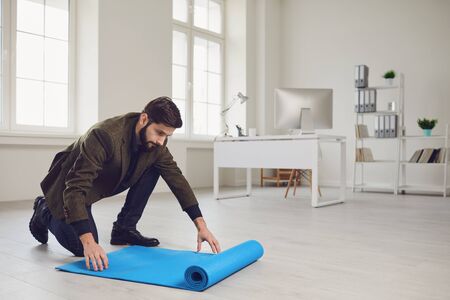 Businessman with yoga mat is standing in office. Gym after work health sport.の写真素材