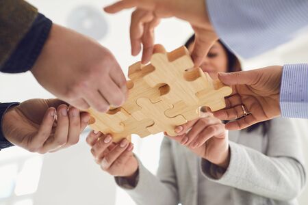 Business people holding wooden gears in their hands connect at a business meeting in the office....