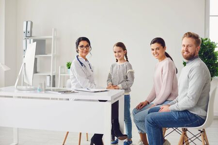 Happy family at the doctors visit at the office. Family doctor standing with smiling family at the clinic.の写真素材