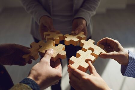 Faceless business people trying to compose all wooden puzzle pieces idea solving problem together
