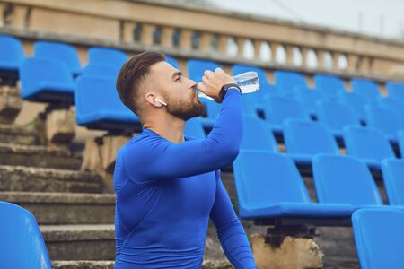 A guy in sportswear is sitting in the stadium after training. Athletic healthy lifestyleの写真素材