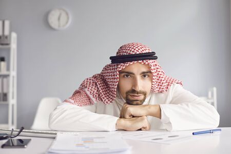 Calm arab man looking sitting at a table in an office room.の写真素材