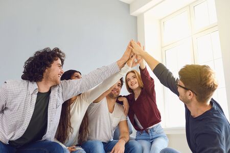 Happy friends cheerfully raised their hands up in a room with a window. Friendship Team Connection...