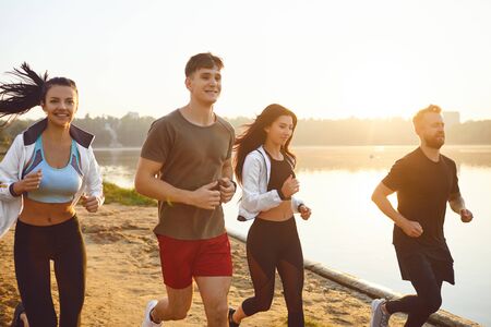 A group of young athletes are running in a park by the lake.の写真素材