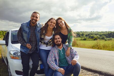 Group of happy people standing next travel in the car on road.