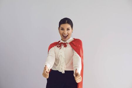 Happy woman in superhero costume laughs thumb up confident happy joyful on gray background.の写真素材