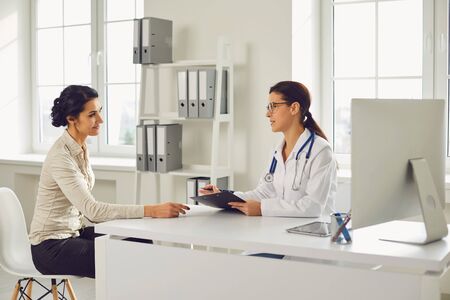 Doctor woman pediatrician gynecologist cardiologist talking client sitting at a table in a clinic office. Medicine clinic hospital.の写真素材