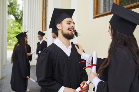 Female graduates with diplomas in their hands hugging laugh at the background of the education, Graduation.University gesture and people concept.の写真素材