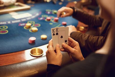 Close-up hands of a poker player checking cards on a table in a casino. Roulette game betting gambling cards poker concept.の写真素材
