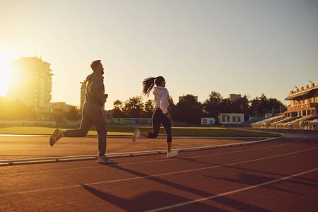 Running in the morning for health.Back view. Athletic couple runs in the morning at the stadium. Jogging during training.Jogging. Health. Healthy lifestyle.の写真素材