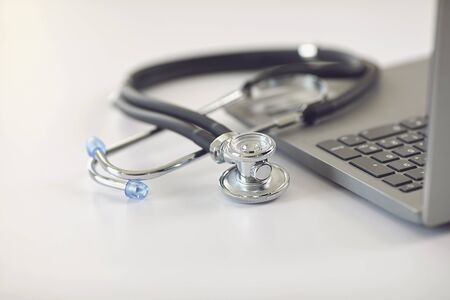 Online doctor call concept. Telemedicine. Stethoscope and laptop on a white table. Online medical consultation diagnosis analysis medicine insurance healthcare using laptop tablet mobile.の写真素材