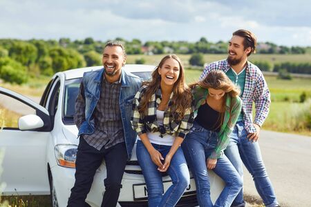 Group of happy people standing next travel in the car on road.の写真素材