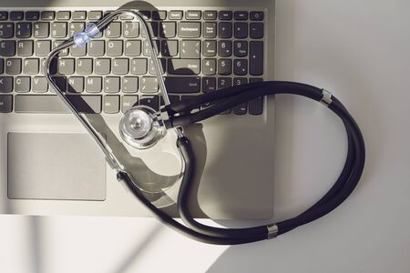 Online doctor call concept. Telemedicine. Stethoscope and laptop on a white table. Online medical consultation diagnosis analysis medicine insurance healthcare using laptop tablet mobile.の写真素材